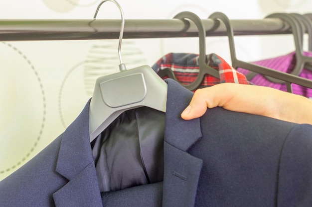 A young man takes a jacket from a hanger for fitting