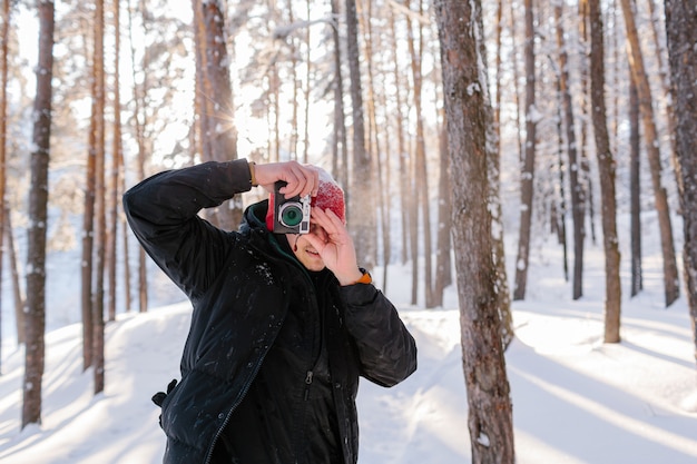 Young man takes photos in winter forest. Fresh snow