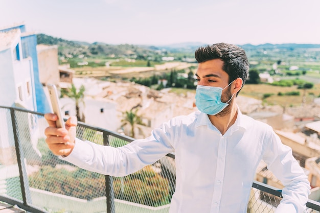 Photo young man takes a picture with a medical mask on, tourism in curentena