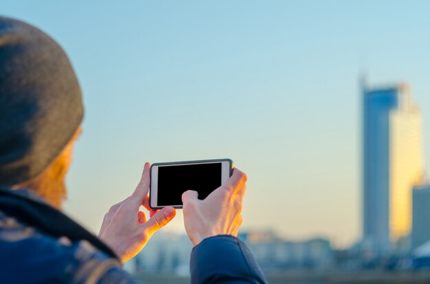 若い男は、スマートフォンで街の写真を撮る