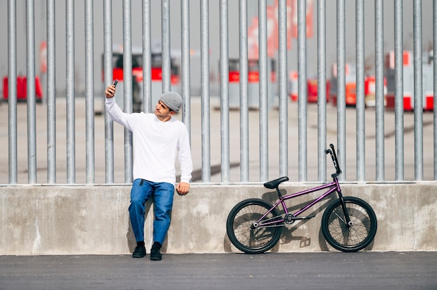 写真 自転車でスマートフォンで写真を撮る青年