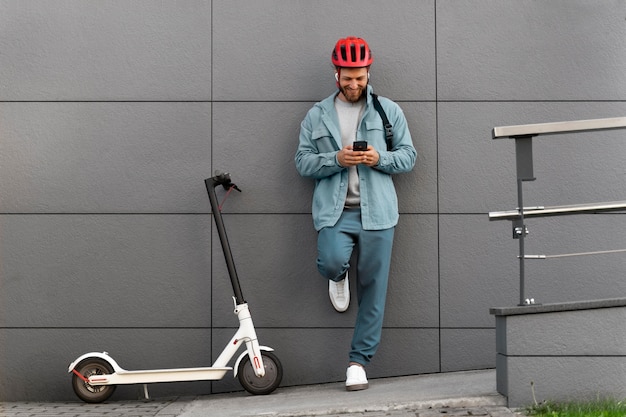 Photo young man taking a break after riding his scooter outside