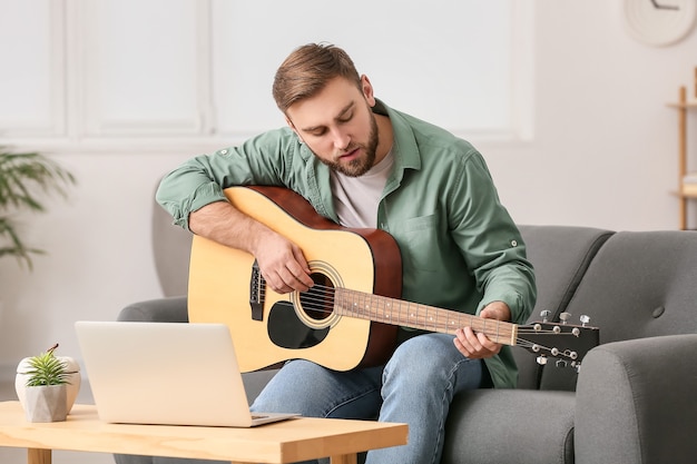 Young man taking music lessons online at home