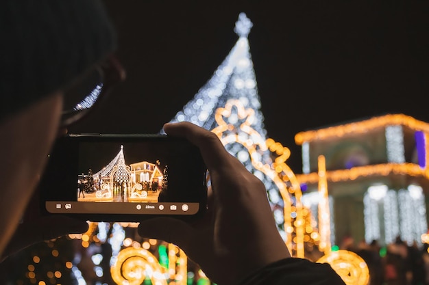 飾られたクリスマスツリーの写真を撮る若い男背景の凱旋門