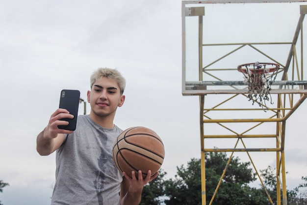 Photo young man taking a selfie on an abandoned basketball court.