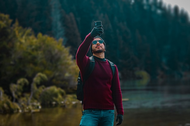 Молодой человек принимает selfie в красивый пейзаж зимой