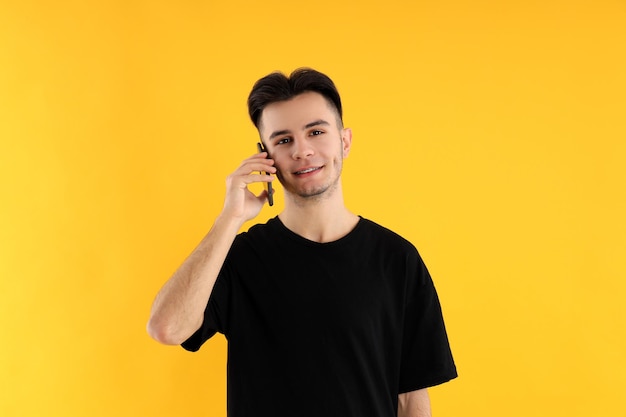 Young man talk on phone on yellow background