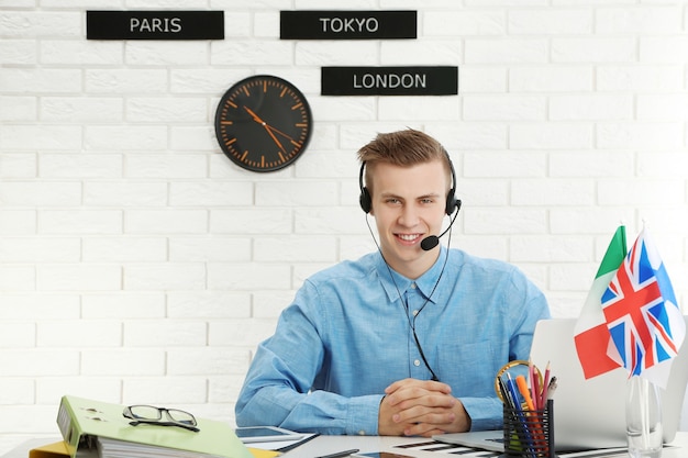 Photo young man talking on headset in the office of travel company