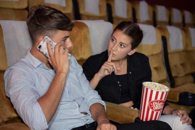 Young man talking on mobile phone during see movie.