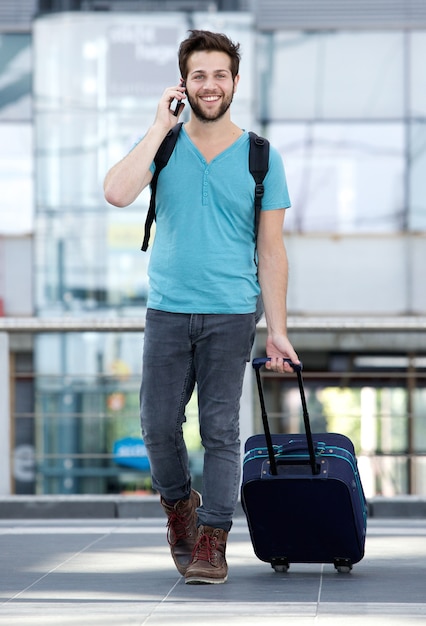 Young man talking on mobile phone with bag