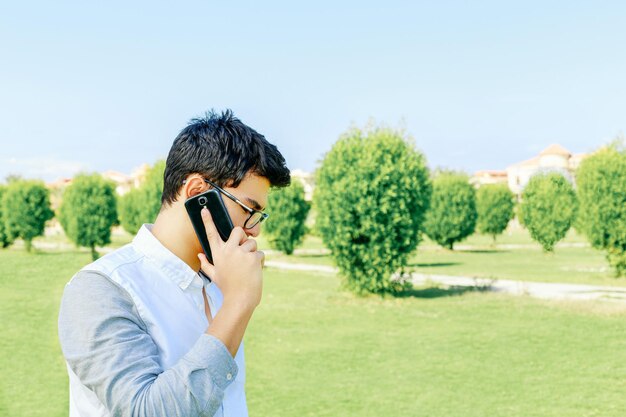 写真 空の向こうのフィールドで携帯電話で話している若者