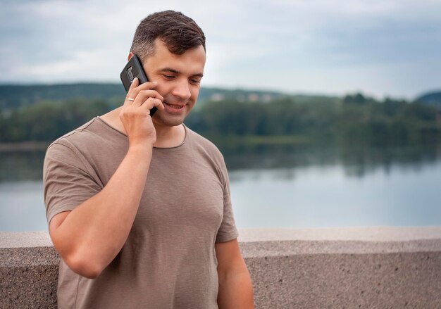 Young man talking on the phone on the background of a lake