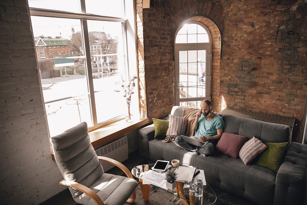 Young man talking on the phone at home while working