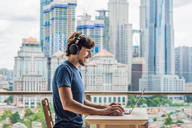 Young man teaches a foreign language or learns a foreign language on the Internet on her balcony against the backdrop of a big city Online language school lifestyle