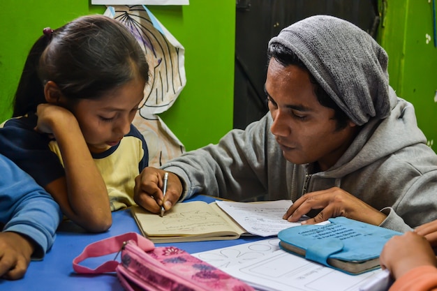 Young man teaches a girl to read and write