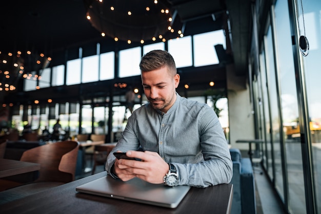 Young man texting in modern restaurant.