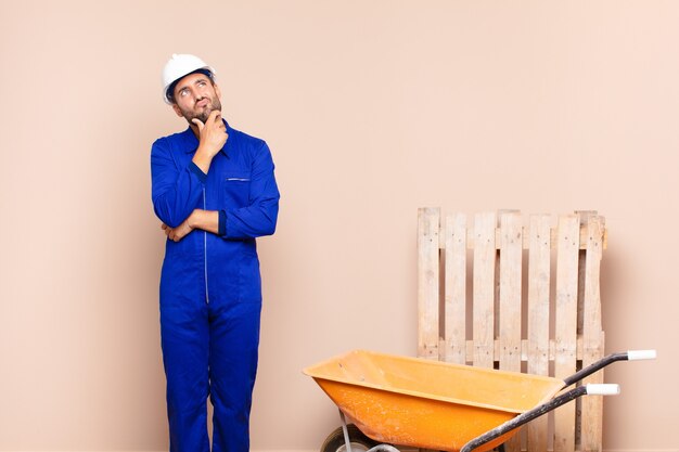 Young man thinking, feeling doubtful and confused, with different options, wondering which decision to make construction concept