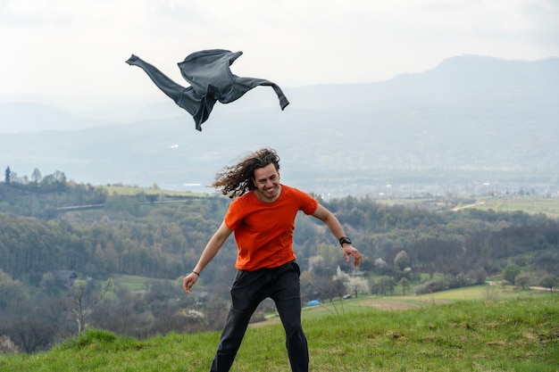 Young man throwing a jacket in the air on mountain