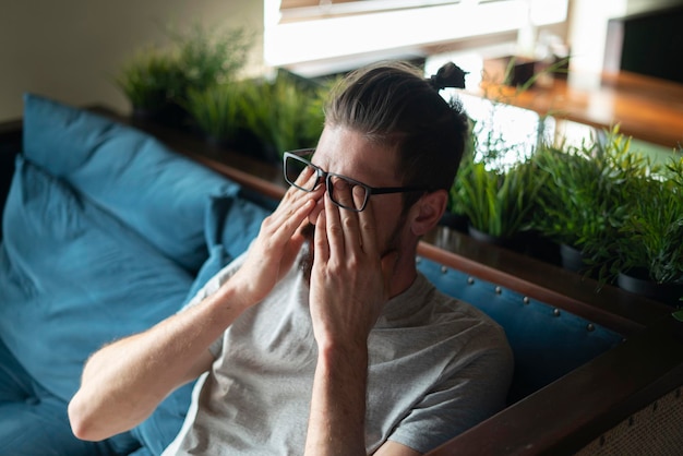 Photo a young man touching eyes, tired wearing eyeglasses