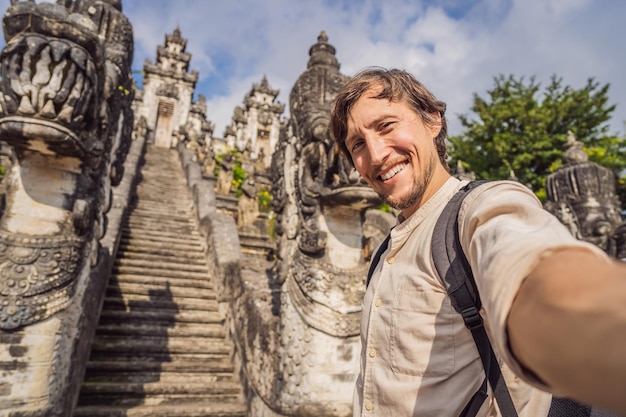 美しいプラ レンプヤン ルフル寺院の背景の 3 つの石造りのはしごの若い男観光客