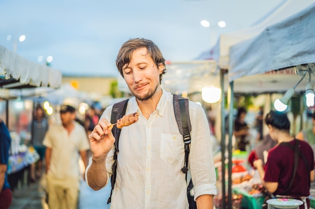 Young man tourist on Walking street Asian food market