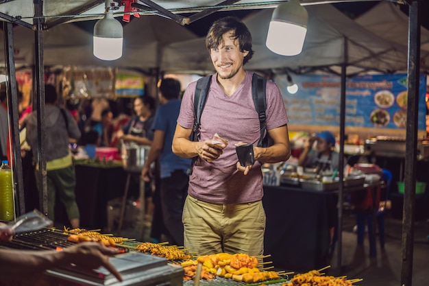 Young man tourist on walking street asian food market