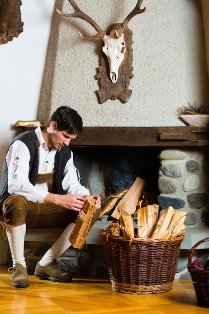 Young man in a traditional mountain hut with fireplace