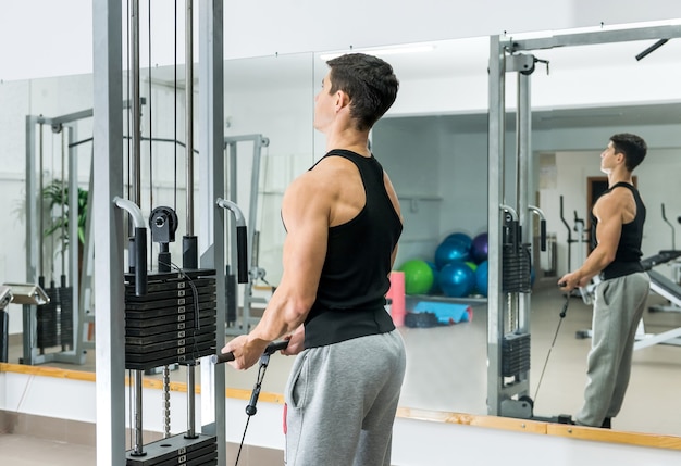 Young man training at sportive equipment in gym