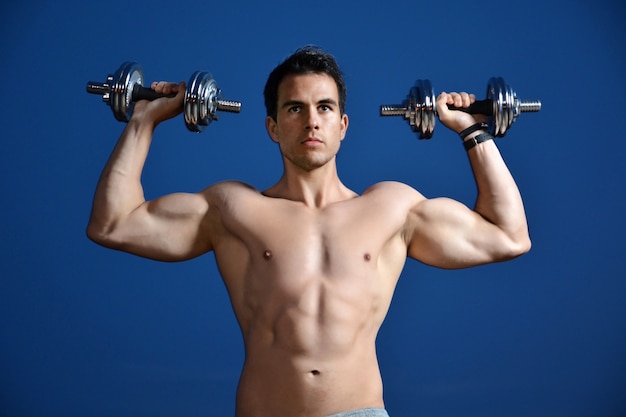 Young man training with dumbbells 