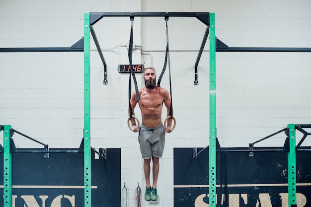 Young man training with rings indoor cross fit gym