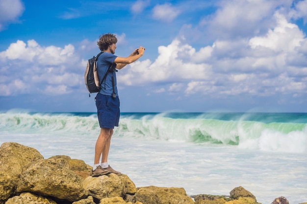 Photo young man traveler on amazing melasti beach with turquoise water bali island indonesia