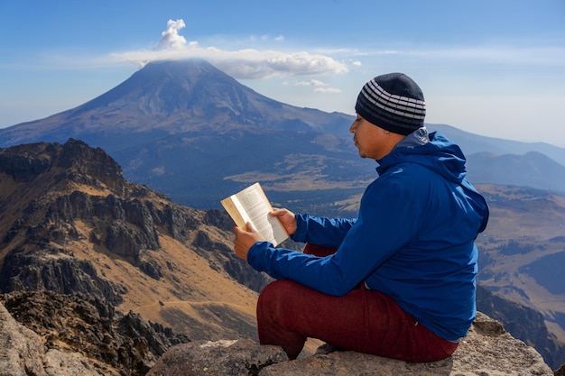 Young Man Traveler met leesboek en schrijven van notities buiten bergen