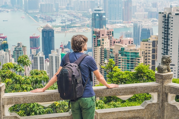 Photo young man traveler at the peak of victoria against the backdrop of hong kong.