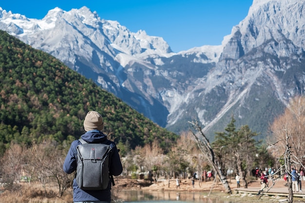 Young man traveler traveling at Blue Moon Valley, landmark and popular spot inside the Jade Dragon Snow Mountain Scenic Area, near Lijiang Old Town. Lijiang, Yunnan, China. Solo travel concept