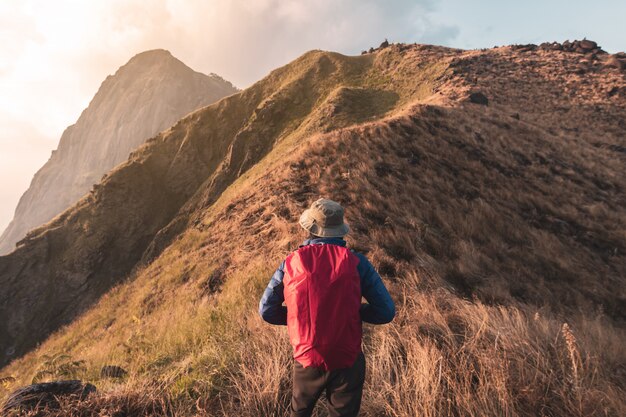 Young man traveler with backpack trekking on mountain