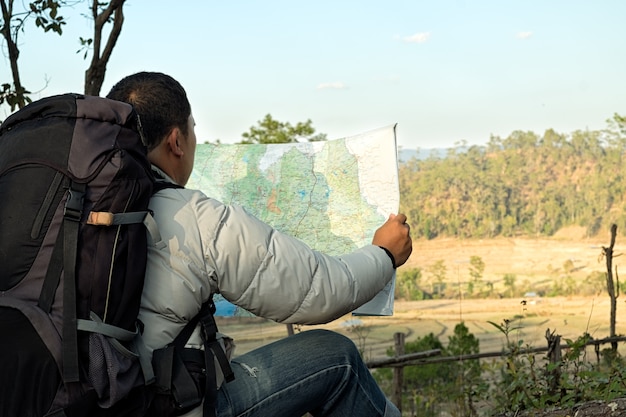 Foto viaggiatore giovane con zaino di cartina rilassante all'aperto con le montagne rocciose sullo sfondo vacanze estive e concetto di trekking di stile di vita