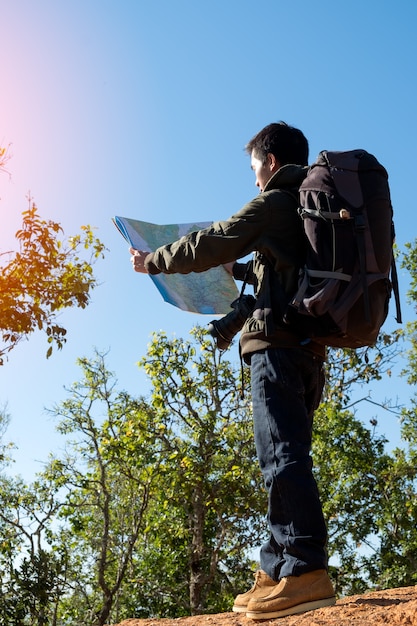 Young Man Traveler with map backpack relaxing outdoor with rocky mountains on background Summer vacations and Lifestyle hiking concept