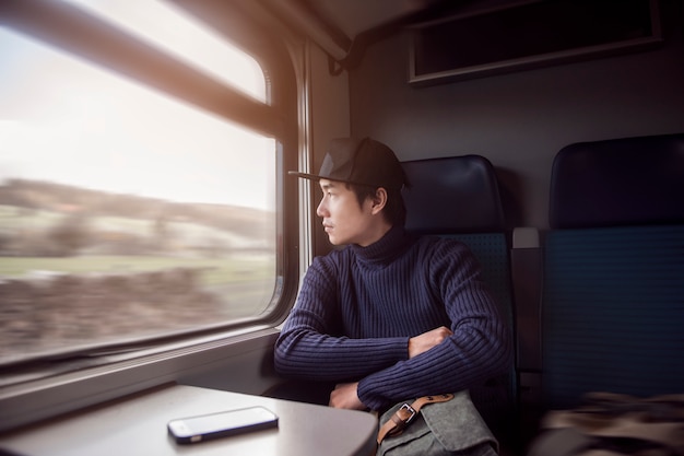 Young man traveling looking out the window while sitting in the train.