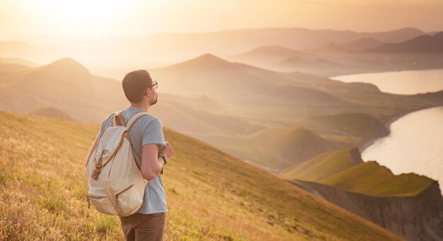 若い男が山を背景に一人旅する