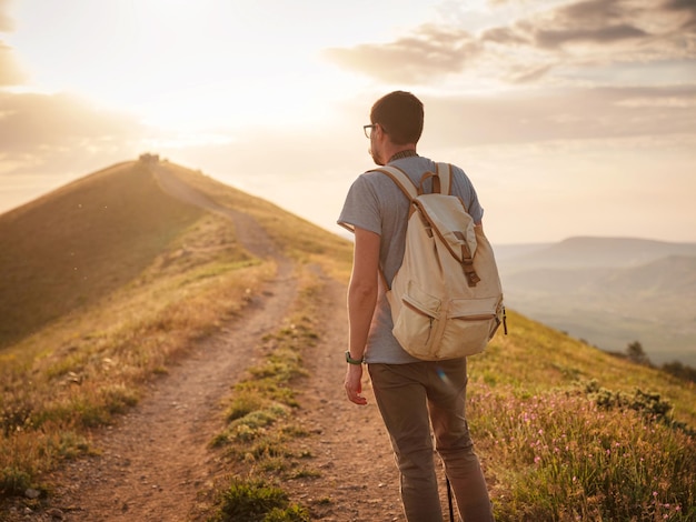 Young man travels alone on the backdrop of the mountains