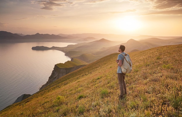 若い男が山を背景に一人旅する