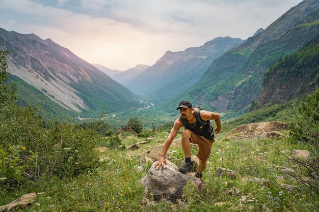 Young man trekking on the top of a green mountain