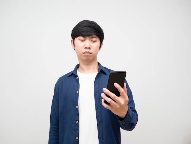 Молодой человек пытается смотреть на мобильный телефон в его руке, проблема с глазами