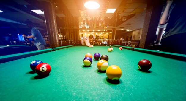 Young man trying to hit the ball in billiard.