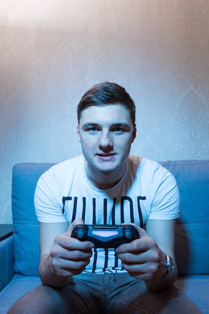 Young man trying to win the video game holding his console in front of him in a close up frontal view sitting on the sofa at home