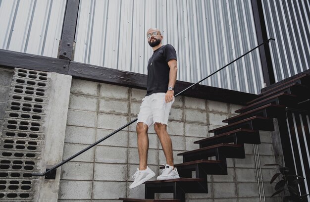 A young man in tshirt and shorts on the stairs at city streets