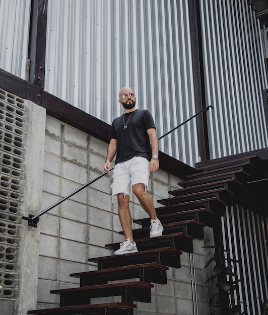 A young man in tshirt and shorts on the stairs at city streets