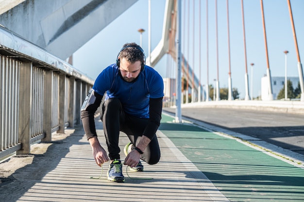 若い男がトレーニング、靴のクローズアップの前にランニングシューズのひもを結ぶ。