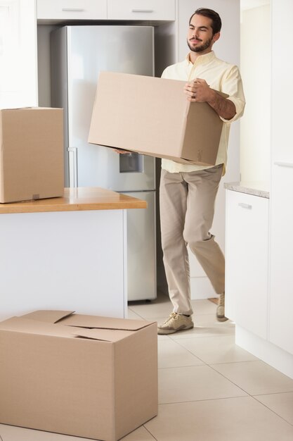 Young man unpacking boxes in kitchen