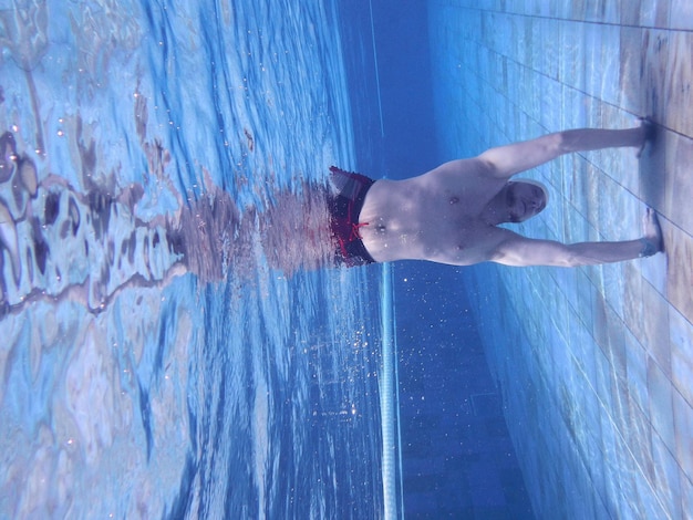 Фото Молодой человек вверх ногами под водой
